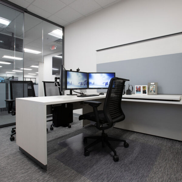 Interior of a private office with height adjustable desk, double monitors, task wall, and open storage