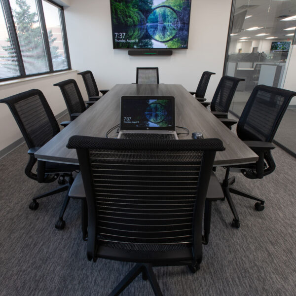 conference room table and chairs with meeting technology, tv, and soundbar