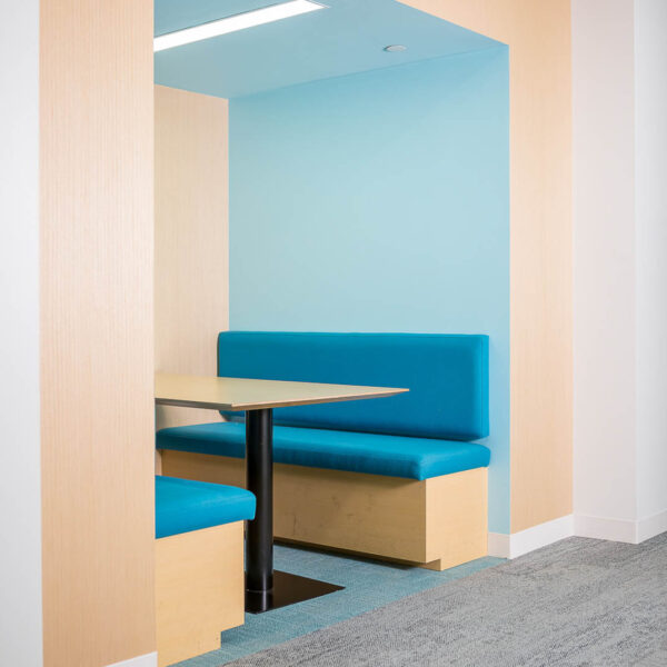 2 blue booths with a table in an surrounding by light wood architecture