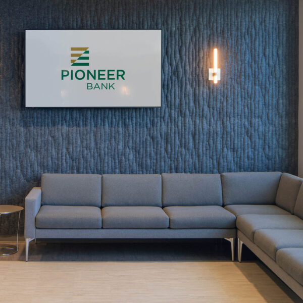 Sectional Couch with Side Table and TV showing the Pioneer Bank Logo