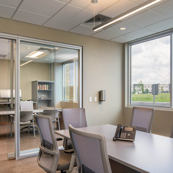 Conference room with task seating, phone on the table, and an architectural glass wall system in the background