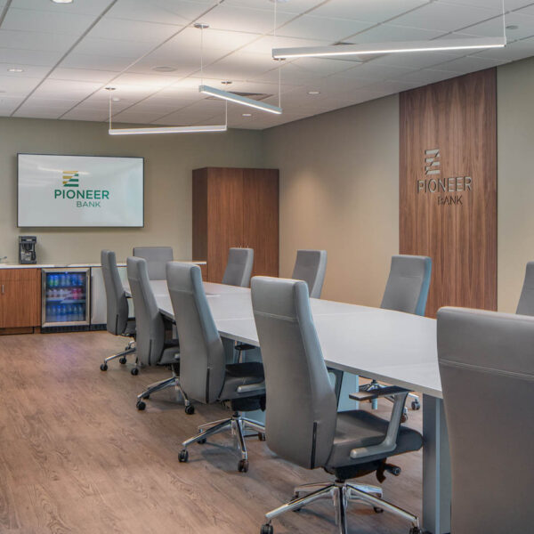 Executive style conference room with high back chairs, a long table, and built in storage and refrigerator credenza