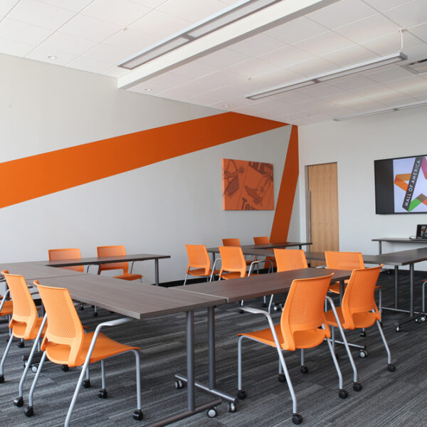 Training room with integrated technology, flip top training tables. and bold orange chairs to enhance branding
