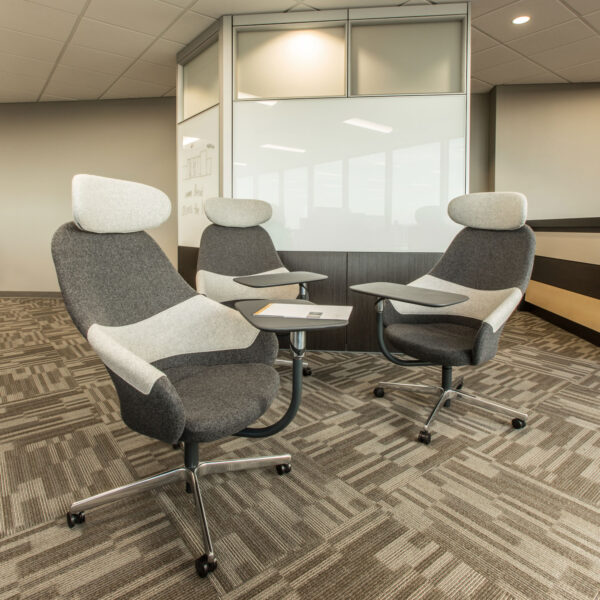 Casual lounge area with modular seating that has built in worksurface and acoustic privacy walls with solid, glass, and whiteboard facias against a warm yellow accent wall
